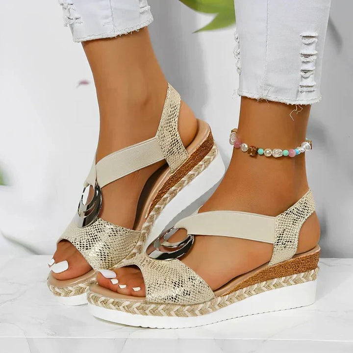 Close-up of a woman wearing beige orthopedic platform sandals with metallic ring detail outdoors.