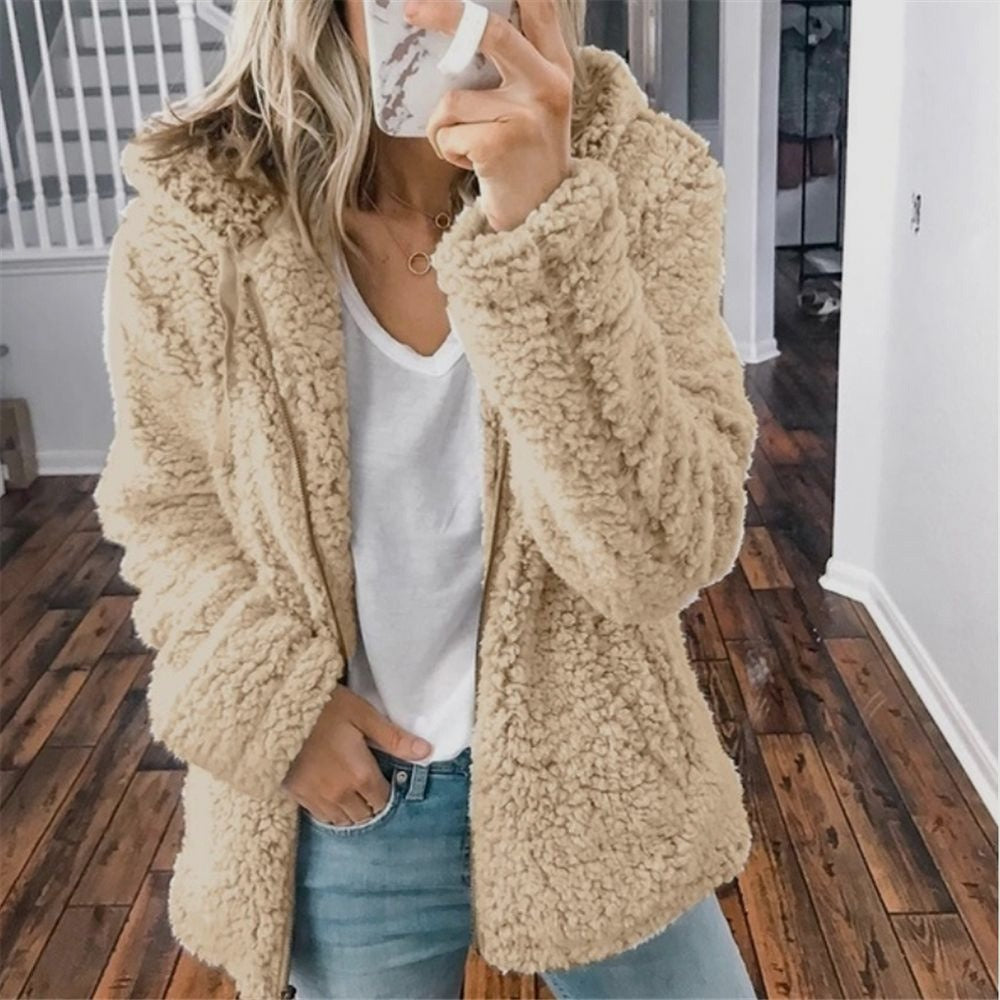 Woman wearing a beige hooded fleece jacket outdoors with denim jeans