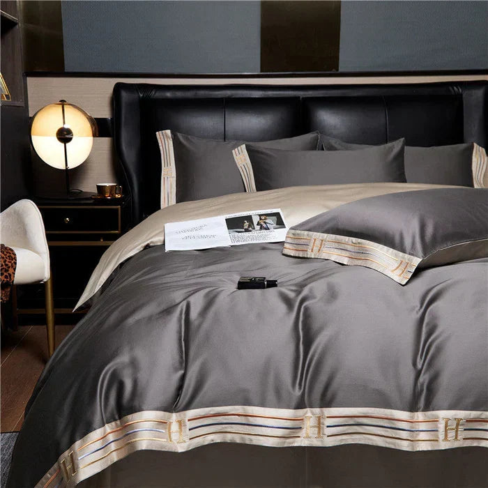 Luxora satin embroidered bedding set in grey styled on a luxury bed
