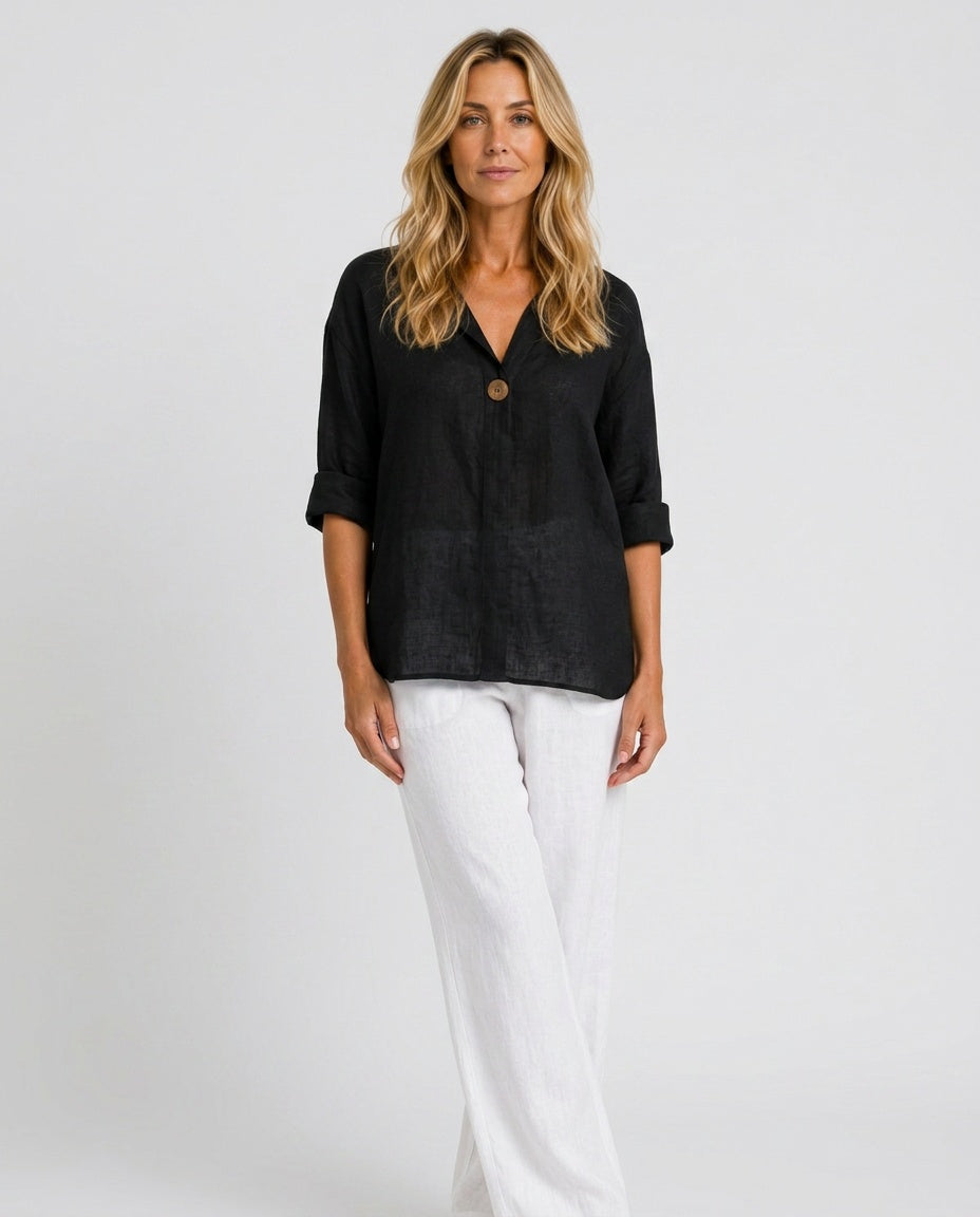 Front view of a woman wearing a black open collar top with white trousers