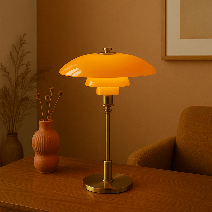 Amber and gold table lamp placed on a wooden desk next to a decorative vase