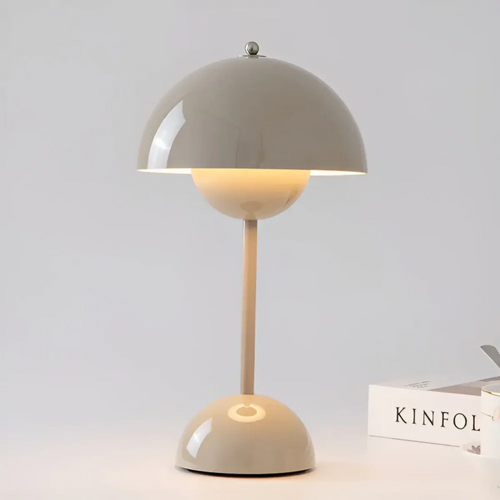 Gray Scandinavian portable table lamp illuminating a minimalist desk setup with neutral decor.