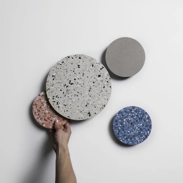 Hand holding a pink terrazzo wall lamp next to other sizes