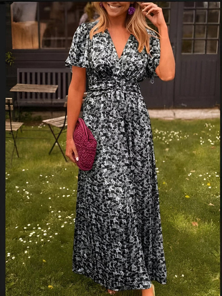 Flat lay of women's floral pleated V-neck maxi dress with accessories for summer fashion