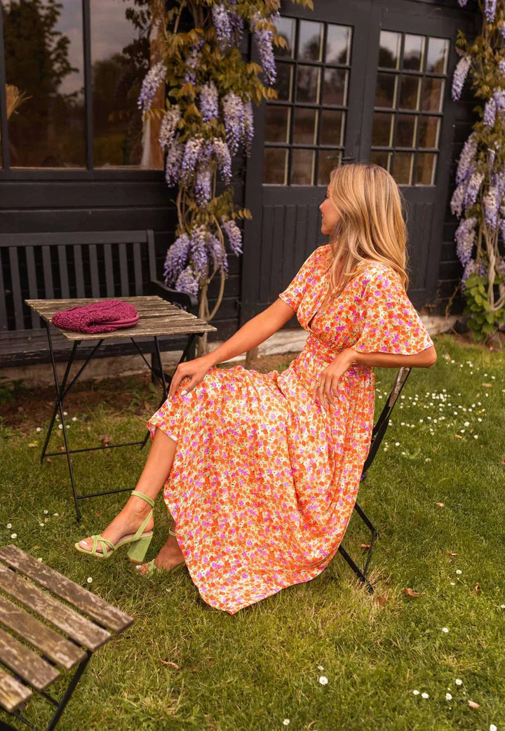 Side view of woman sitting in a floral maxi dress outdoors