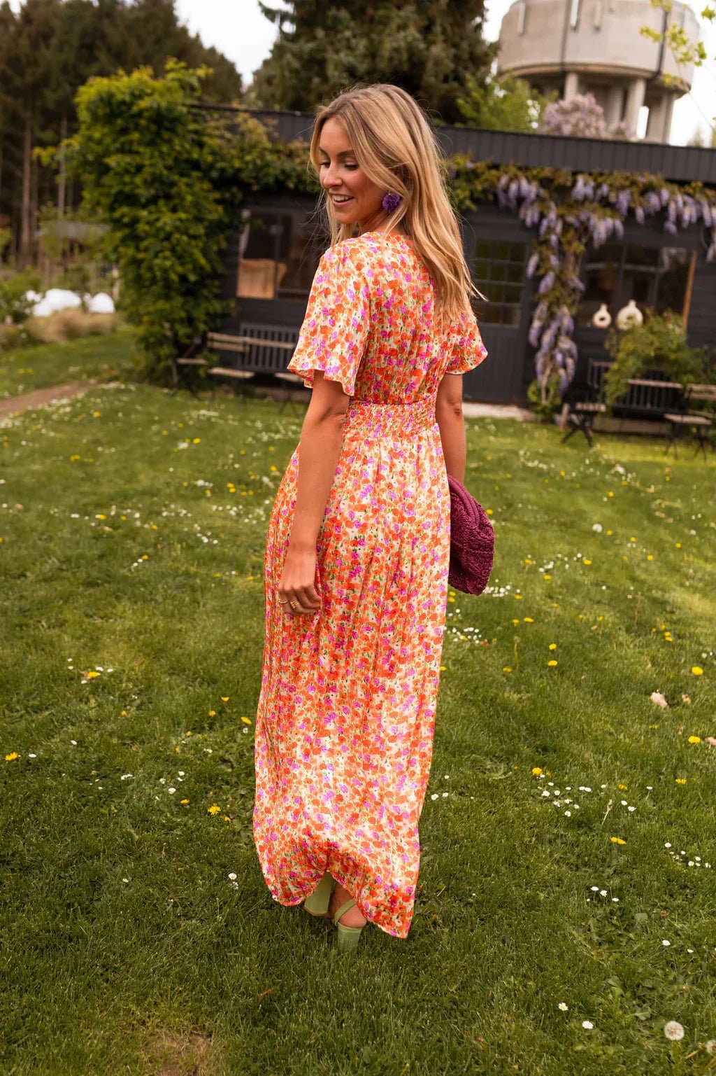 Back view of woman walking in a vibrant floral maxi dress