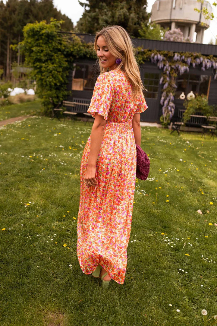 Back view of woman walking in a vibrant floral maxi dress