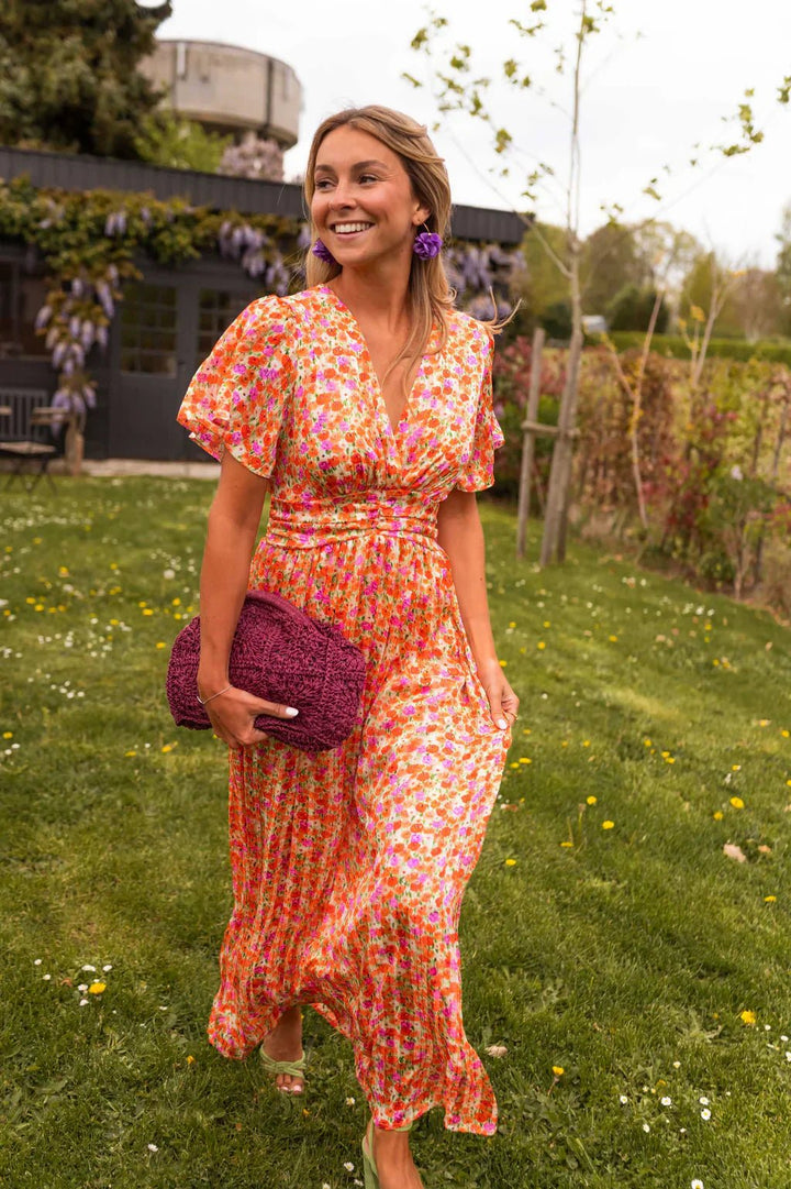 Women's floral pleated V-neck maxi dress back view showing flowing skirt and elegant design