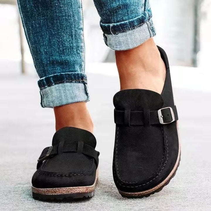 Close-up of black women's slip-on buckle loafers worn with denim jeans