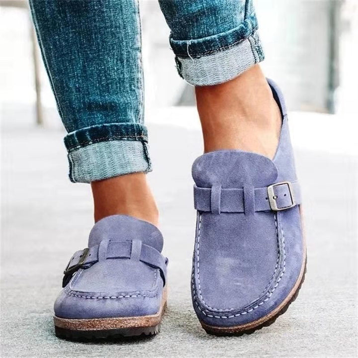Close-up of purple women's slip-on buckle loafers worn with denim jeans