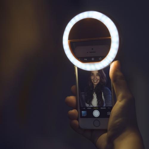 Portable selfie ring light clipped onto a smartphone for content creation and video calls