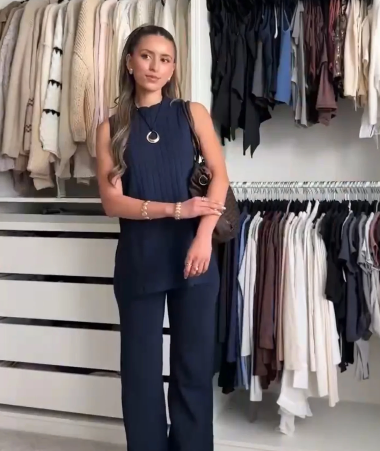 Full-length view of a woman posing in a dark blue sleeveless top and matching trousers