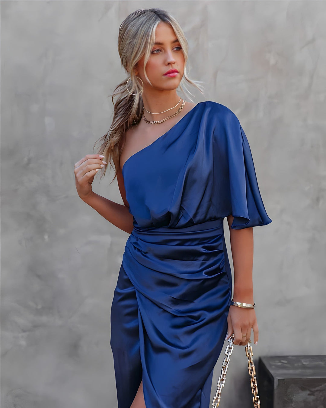 Model wearing blue Amara evening dress posing against a grey wall