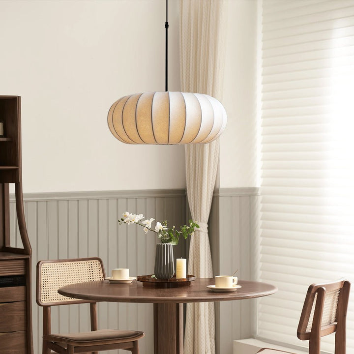 Ambient light from contemporary silk pendant lamp styled over a wooden table