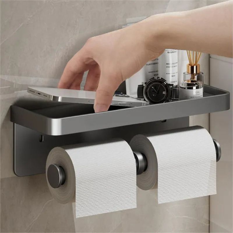 Hand placing a smartphone on the silver multifunctional toilet roll holder shelf