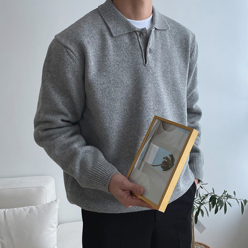 Man wearing a grey long sleeve button polo sweater holding a framed picture