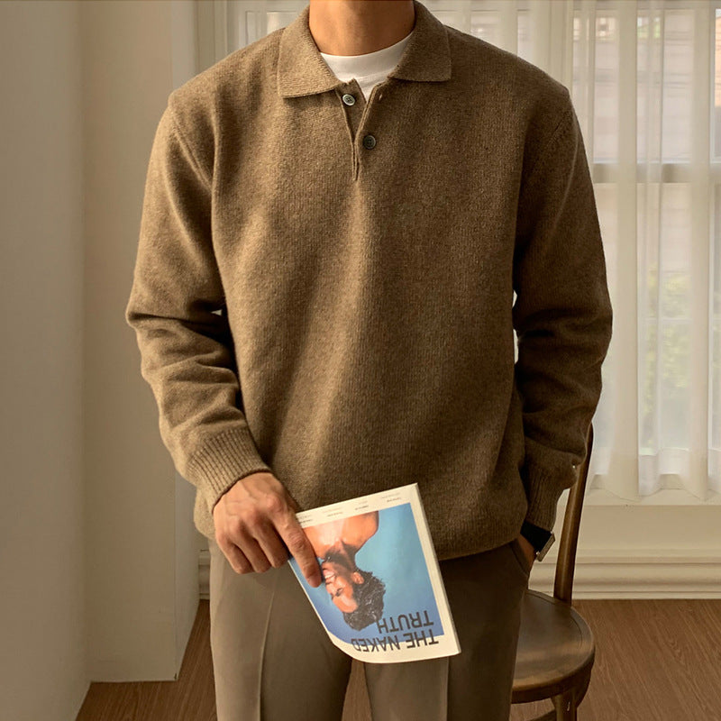Man wearing a brown long sleeve button polo sweater holding a magazine