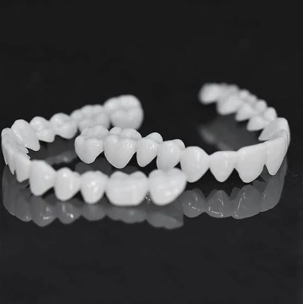 Upper and lower jaw snap lock denture set on dark reflective surface