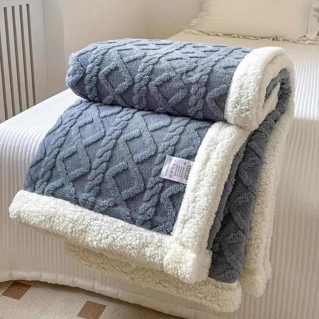 Soft blue textured fleece blanket folded on a white bed setup