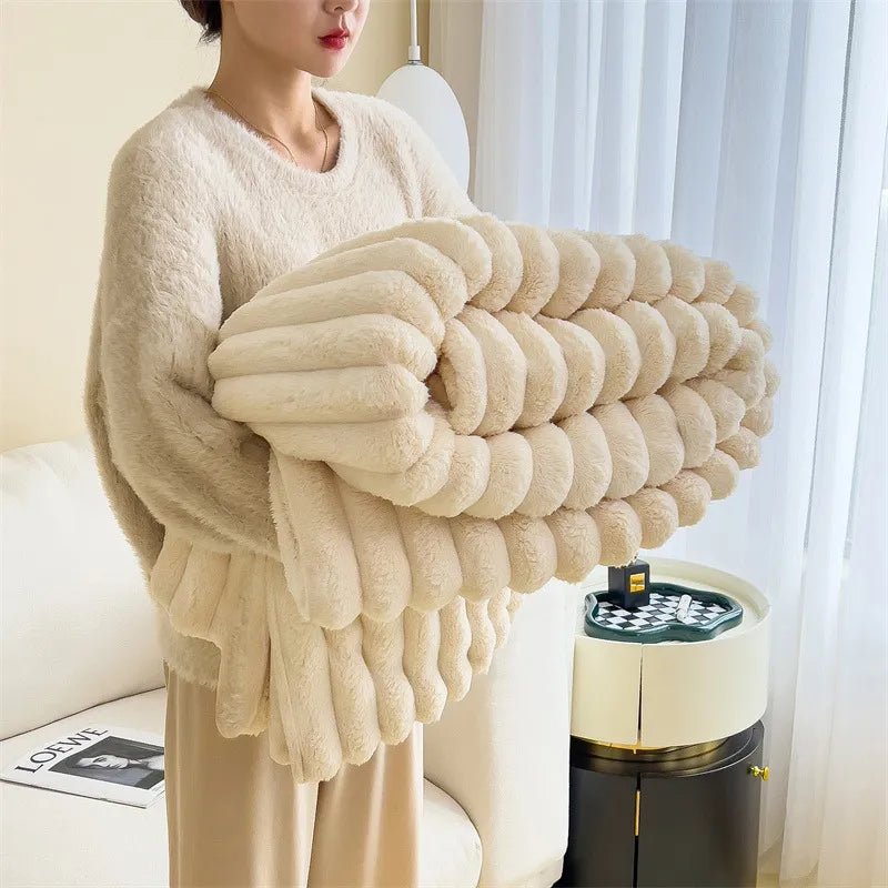 Person holding a folded cream soft plush throw blanket in a bright room