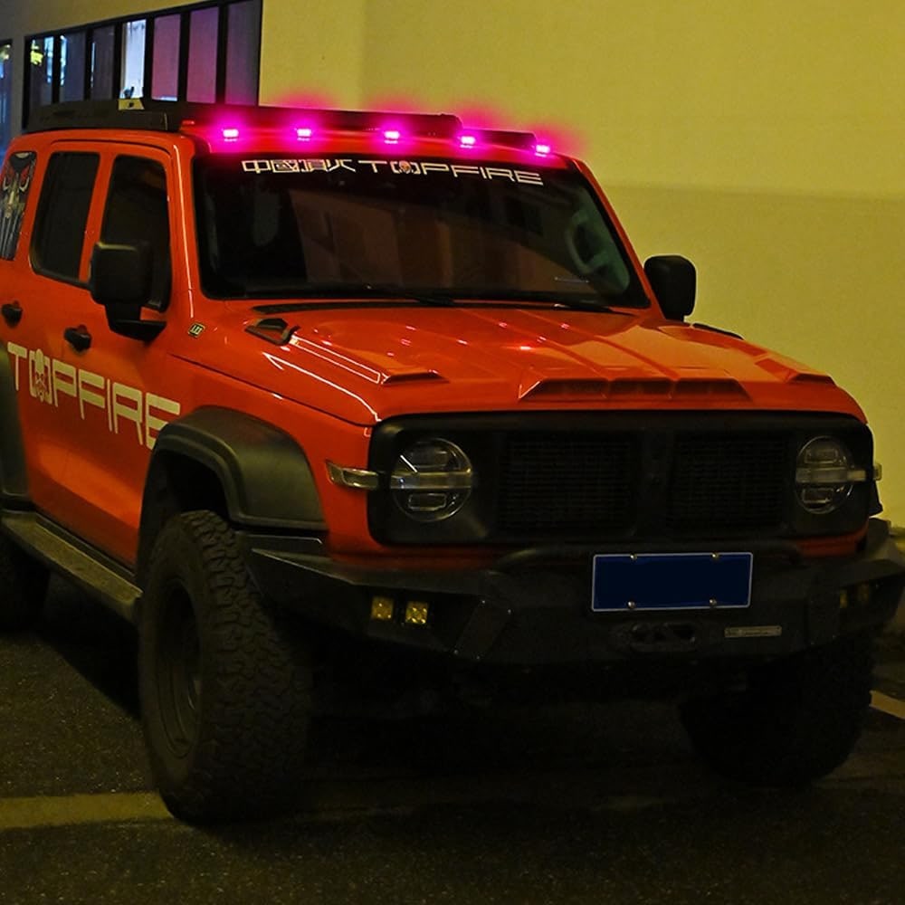 An off-road truck mounted with pink solar rock lights along the roofline at night.