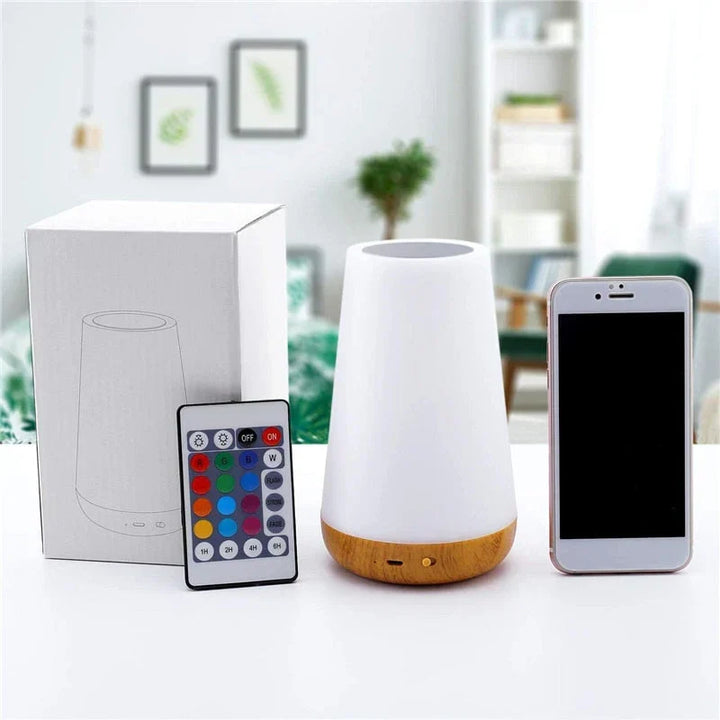 Night light displayed next to its retail box, remote, and smartphone