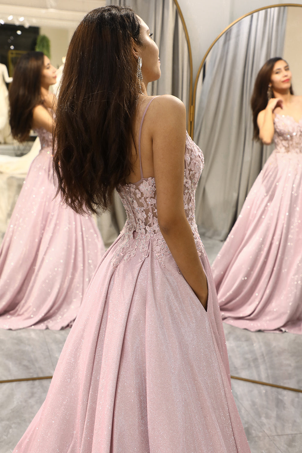 Side view of woman showcasing the back design and details of the blush pink gown