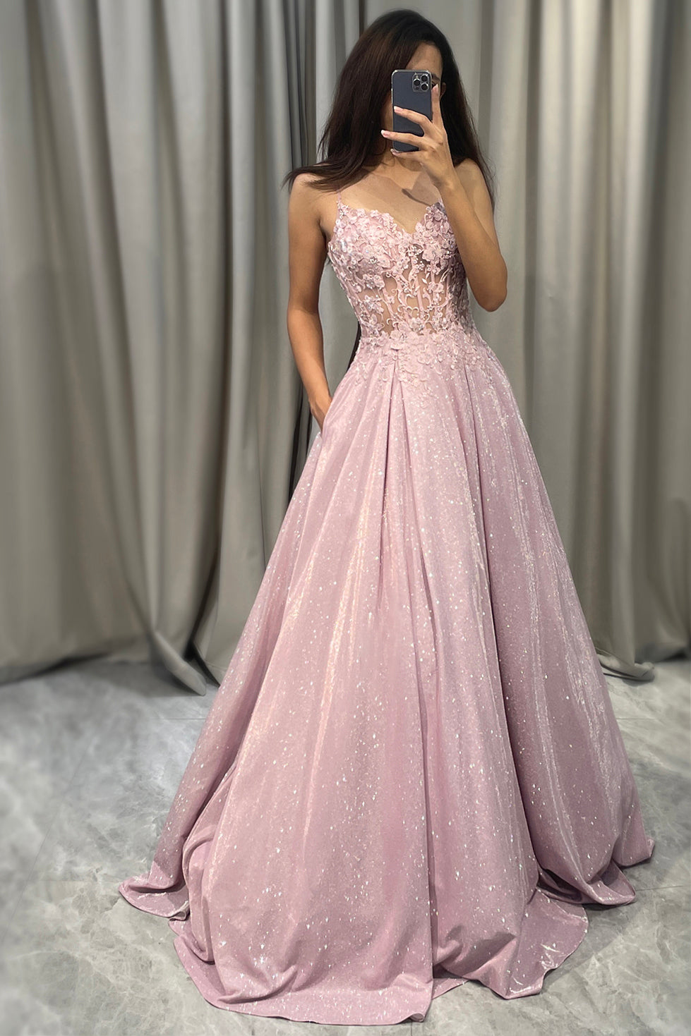 Woman wearing sparkling blush pink A-line ball gown in front of a mirror