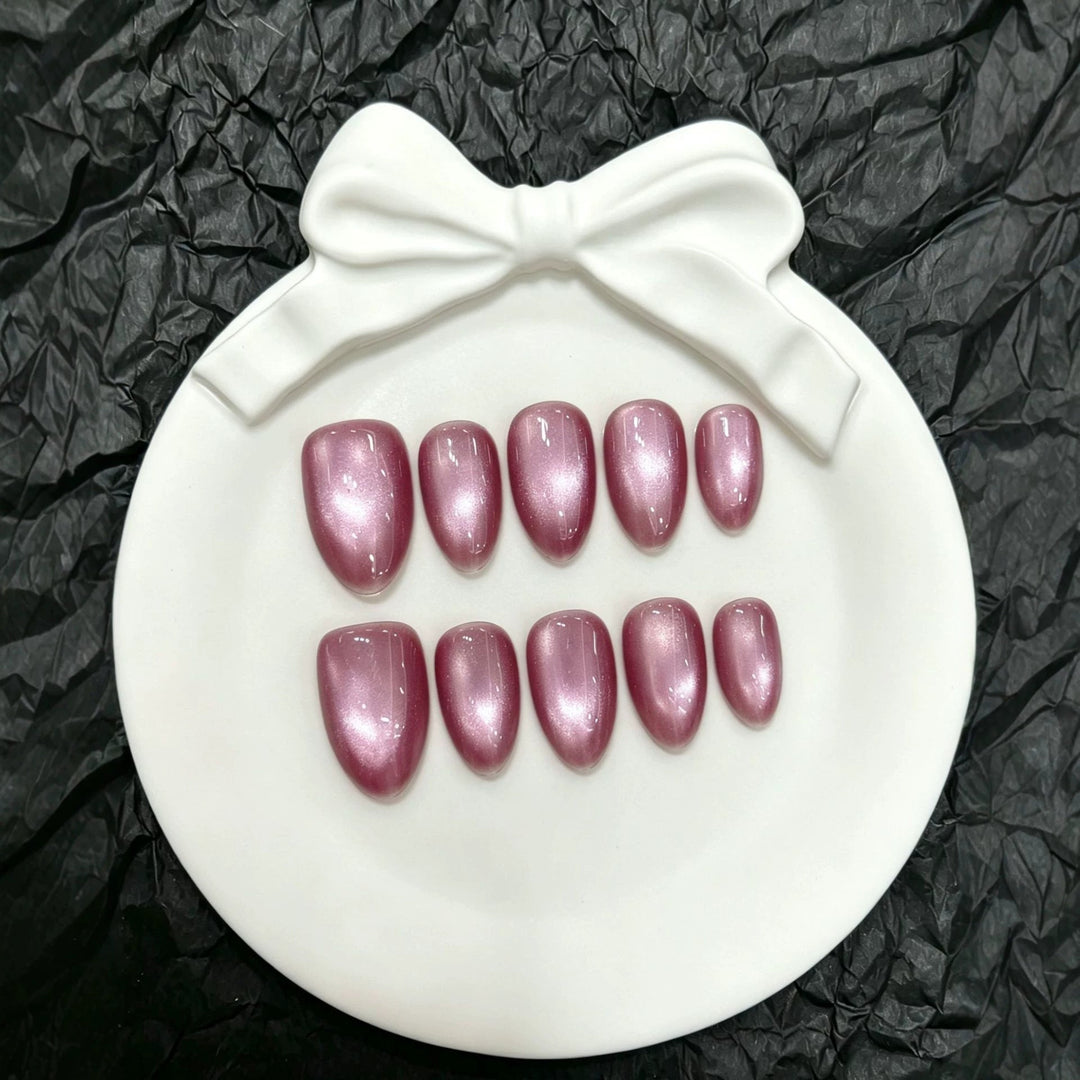 Top view of the glossy pink press-on nail set arranged on a white ceramic dish
