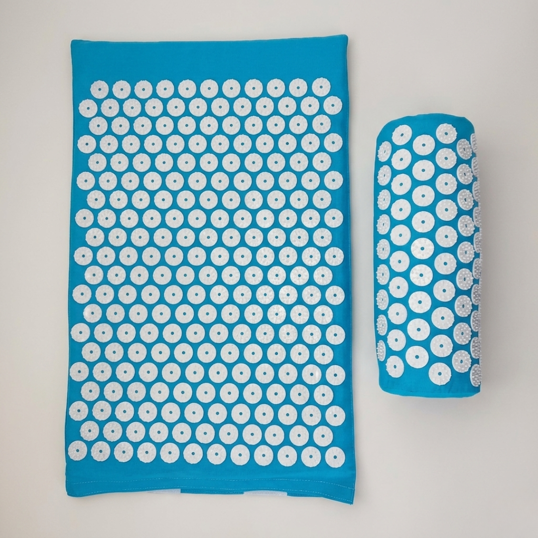 Green acupressure mat and pillow set for back pain relief and muscle recovery on wooden floor