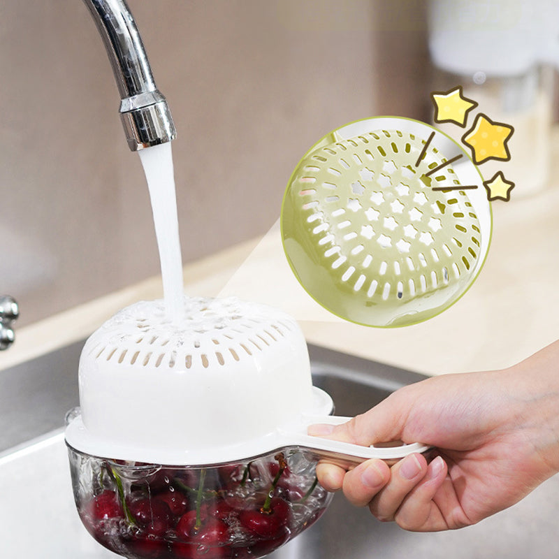 Hand rinsing cherries inside a white kitchen drainer basket under running water