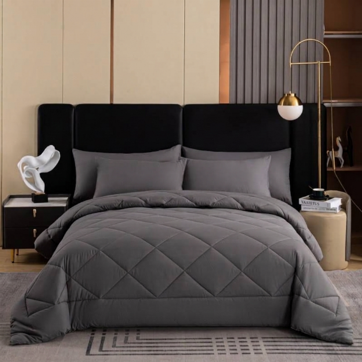 Grey quilted bedspread set displayed on a modern platform bed with matching pillow shams