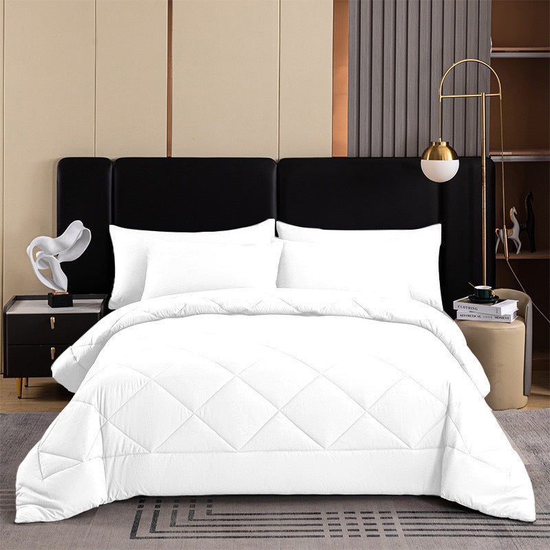 Crisp white quilted comforter set styled cleanly on a bed in a contemporary bedroom
