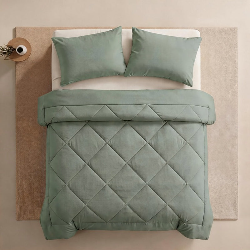 Sage green quilted comforter set displayed on a bed with two matching pillowcases