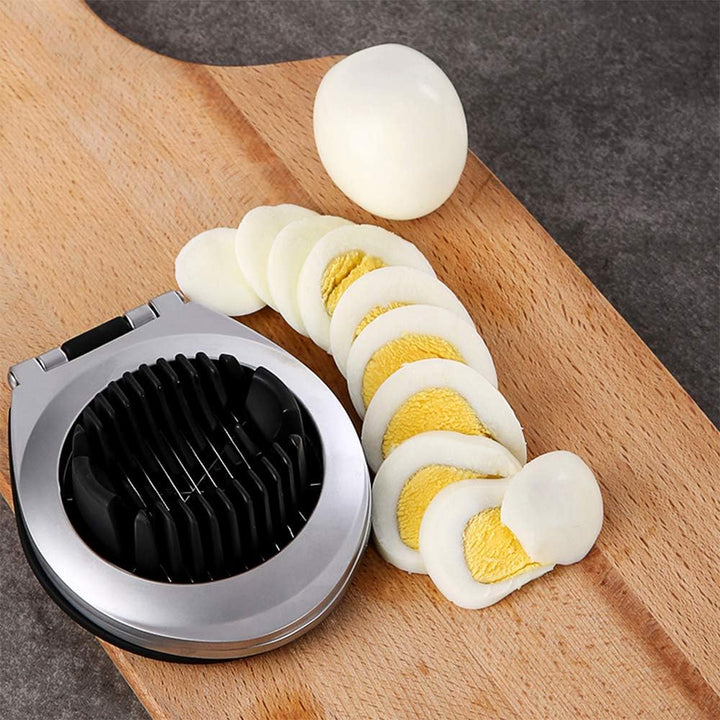 Sliced hard-boiled egg next to stainless steel egg cutter