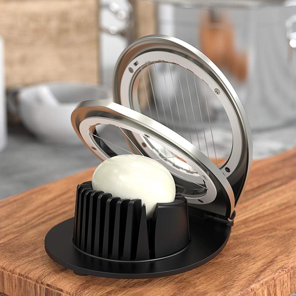 Stainless steel egg slicer with black base on wooden board