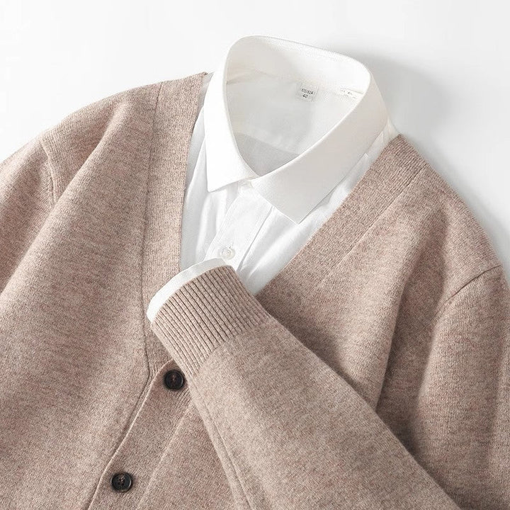 Close-up of beige men's v-neck cardigan collar and button detail layered over a white shirt