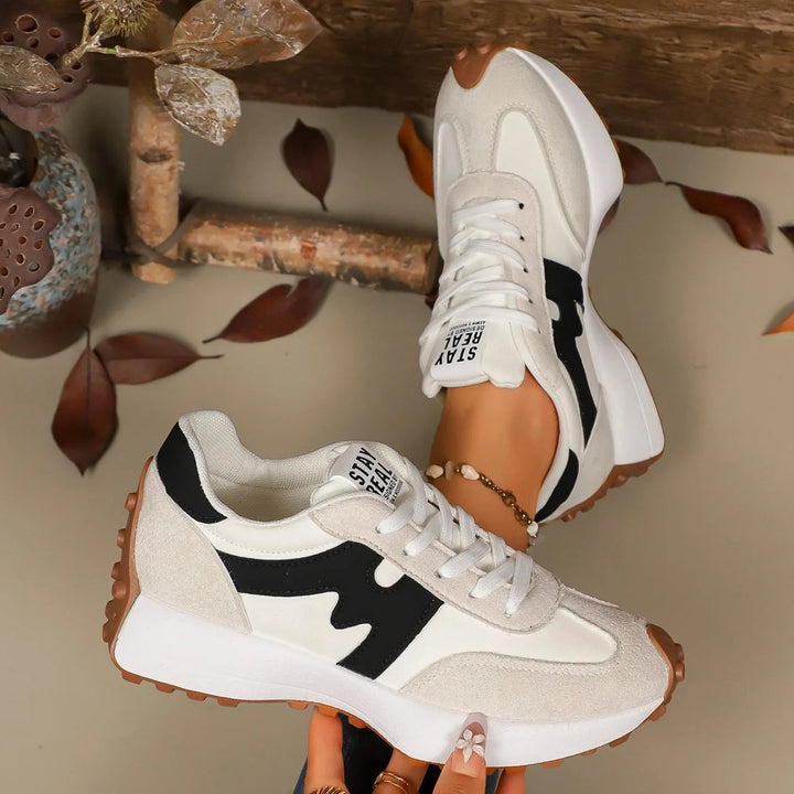 Women's white striped platform sneakers displayed on rustic background