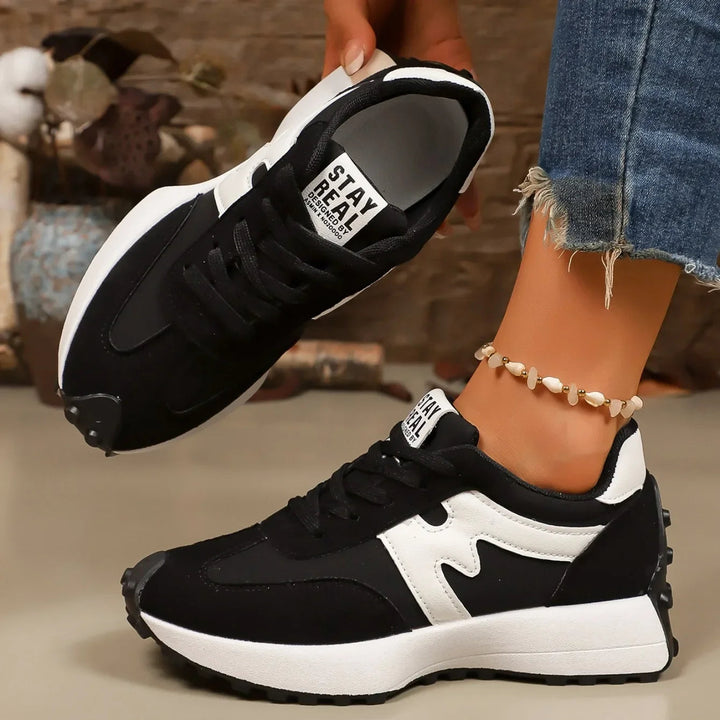 Women's black striped platform sneakers held up showcasing sole details