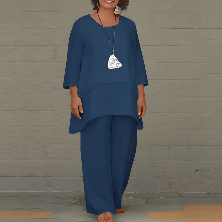 A woman wearing a stylish blue two-piece set featuring a long sleeve top and matching trousers.