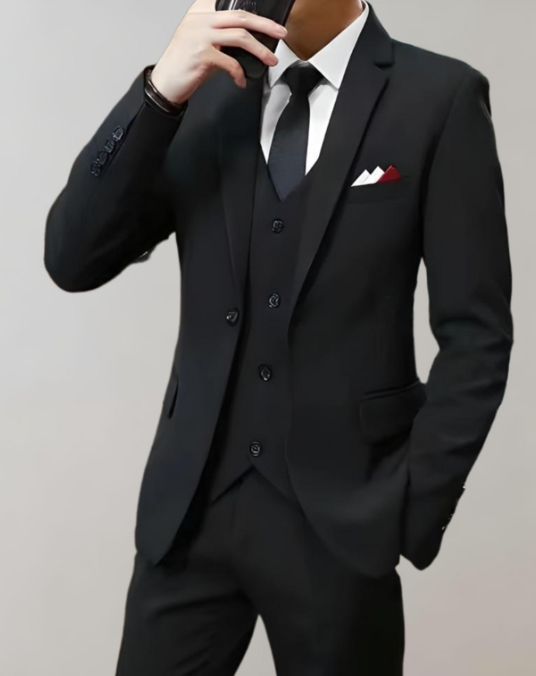 Man wearing a black 3-piece men's suit holding a phone