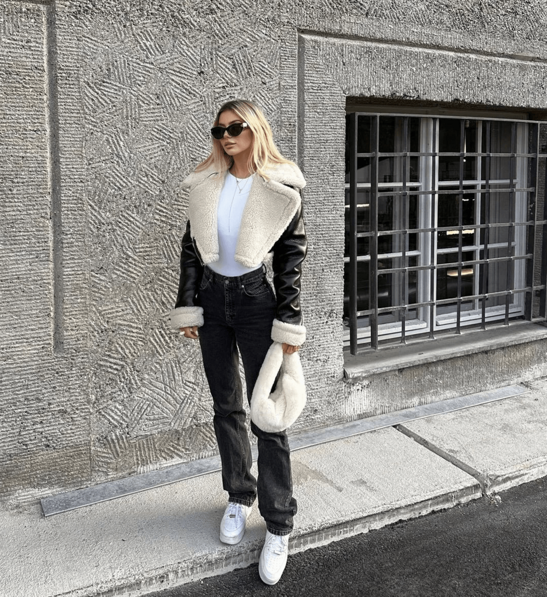Stylish woman wearing a black winter jacket with faux fur collar outdoors