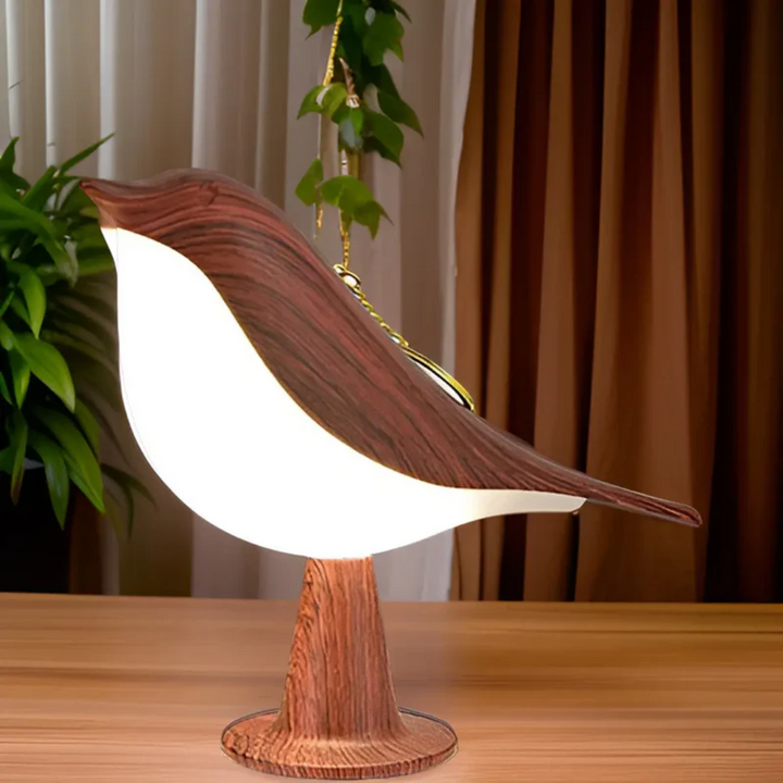 Brown LED bird lamp standing on a wooden surface next to indoor plants
