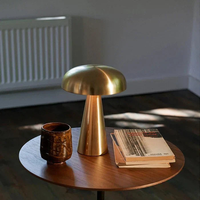 Close-up view of the gold mushroom table lamp glowing on a wooden table