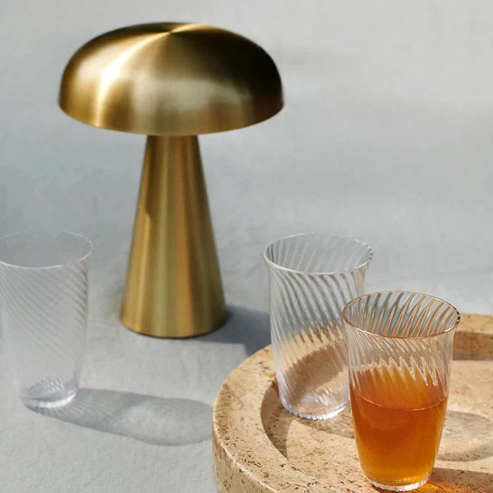 Gold mushroom table lamp next to glass cups on a tray in natural sunlight