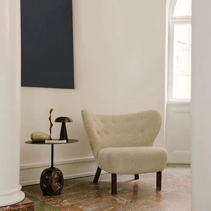Portable mushroom table lamp placed on a black side table beside a textured armchair