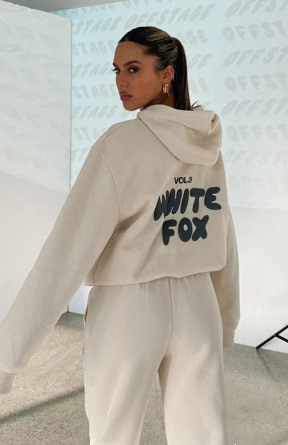 Woman wearing cream oversized hooded tracksuit with bold back graphic