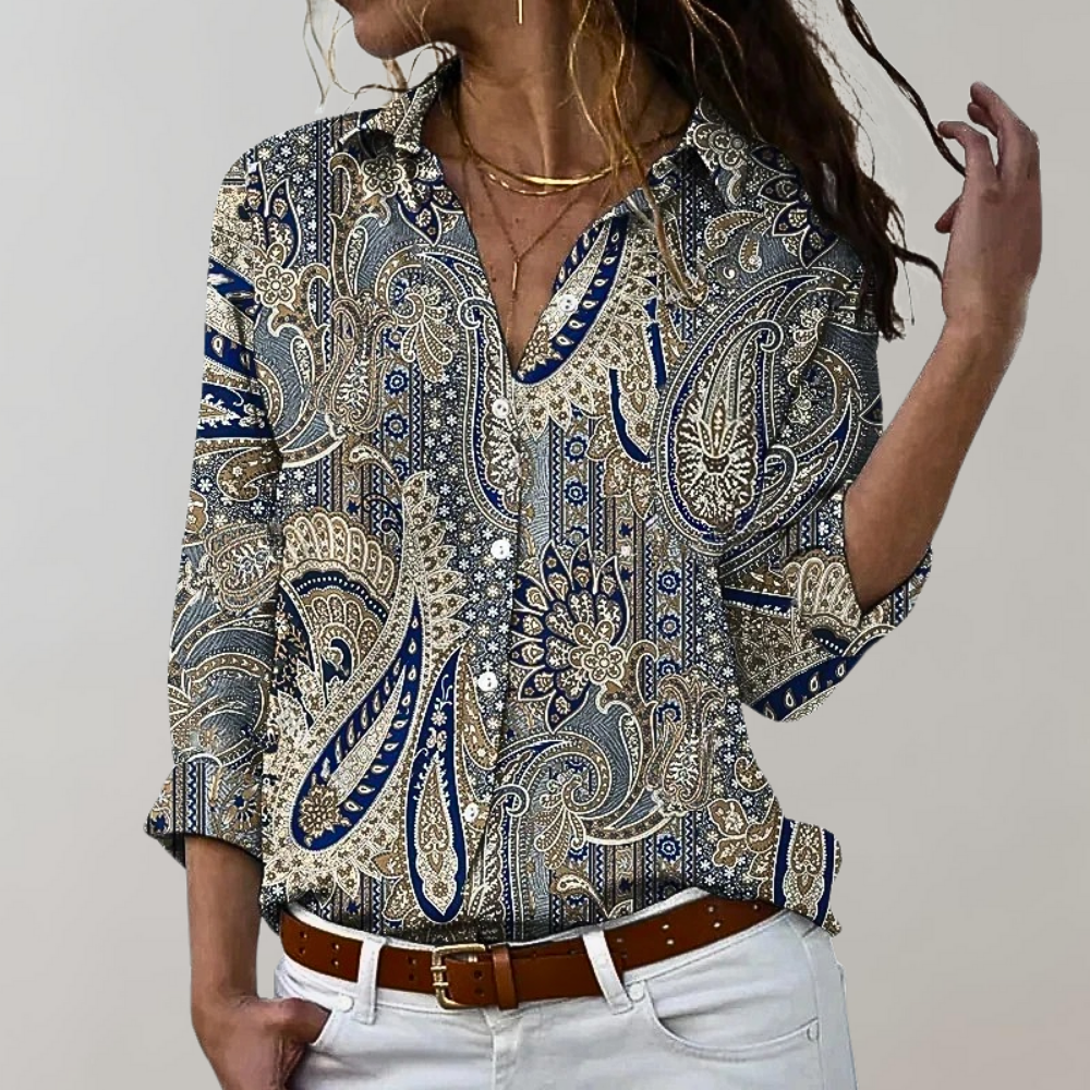 Woman wearing grey paisley patterned button-down blouse with white pants