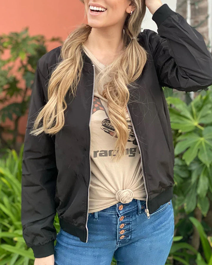 Woman smiling in a casual black bomber jacket paired with jeans