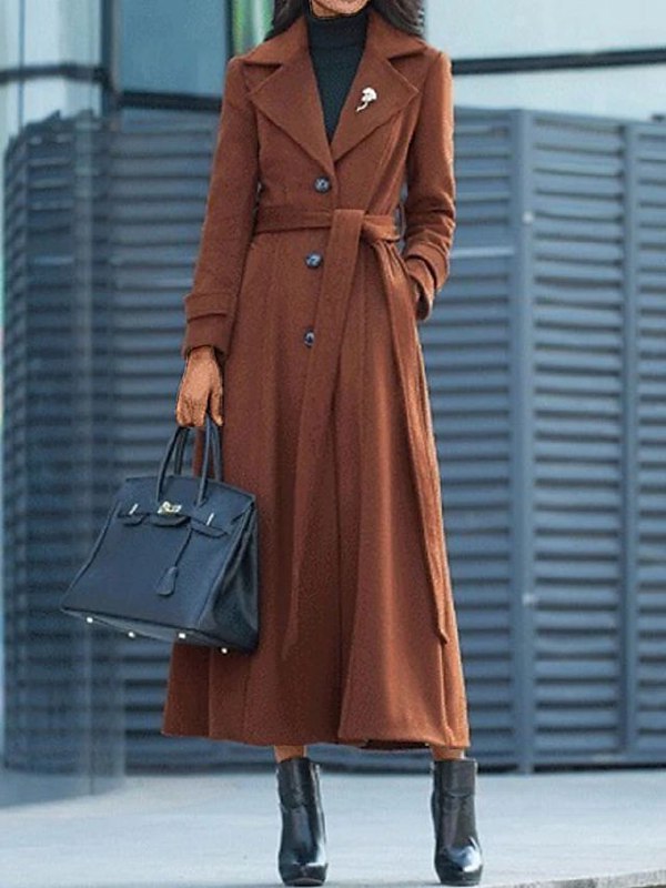 Full length brown women's winter coat styled with a matching belt and handbag